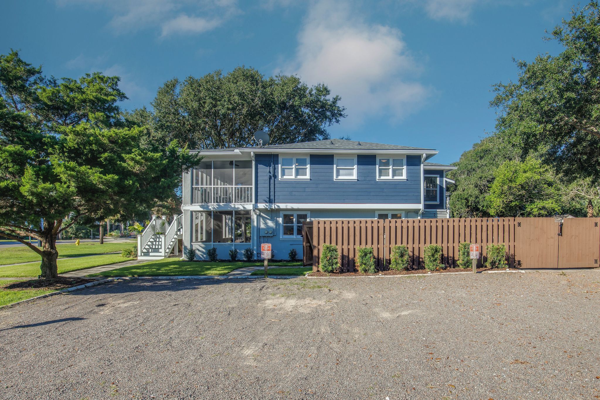 A two-story house with a front porch, a driveway, and a fenced yard.