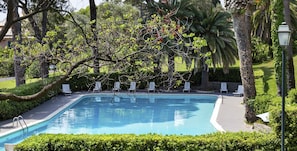 Ein Pool mit Liegestühlen und einer Hecke.