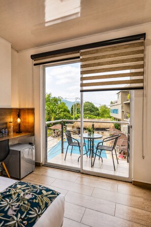 Une chambre d’hôtel avec un balcon, une piscine et un lit.