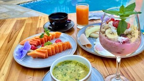 Ein Tisch mit Mahlzeit, einem Getränk und Blick auf den Pool.