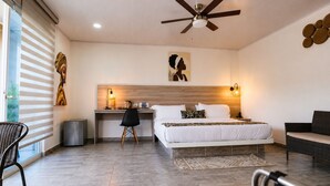 Ein Hotelzimmer mit Bett, Schreibtisch, Stuhl und Deckenventilator.