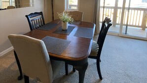 Un comedor con una mesa de madera, cuatro sillas, una lámpara colgante y una planta en maceta.