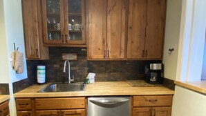 Una cocina con armarios de madera, lavavajillas de acero inoxidable y cafetera.