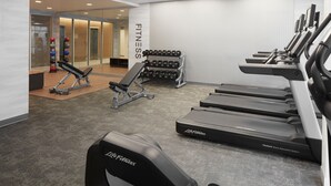 A gym with treadmills, dumbbells, and a bench.