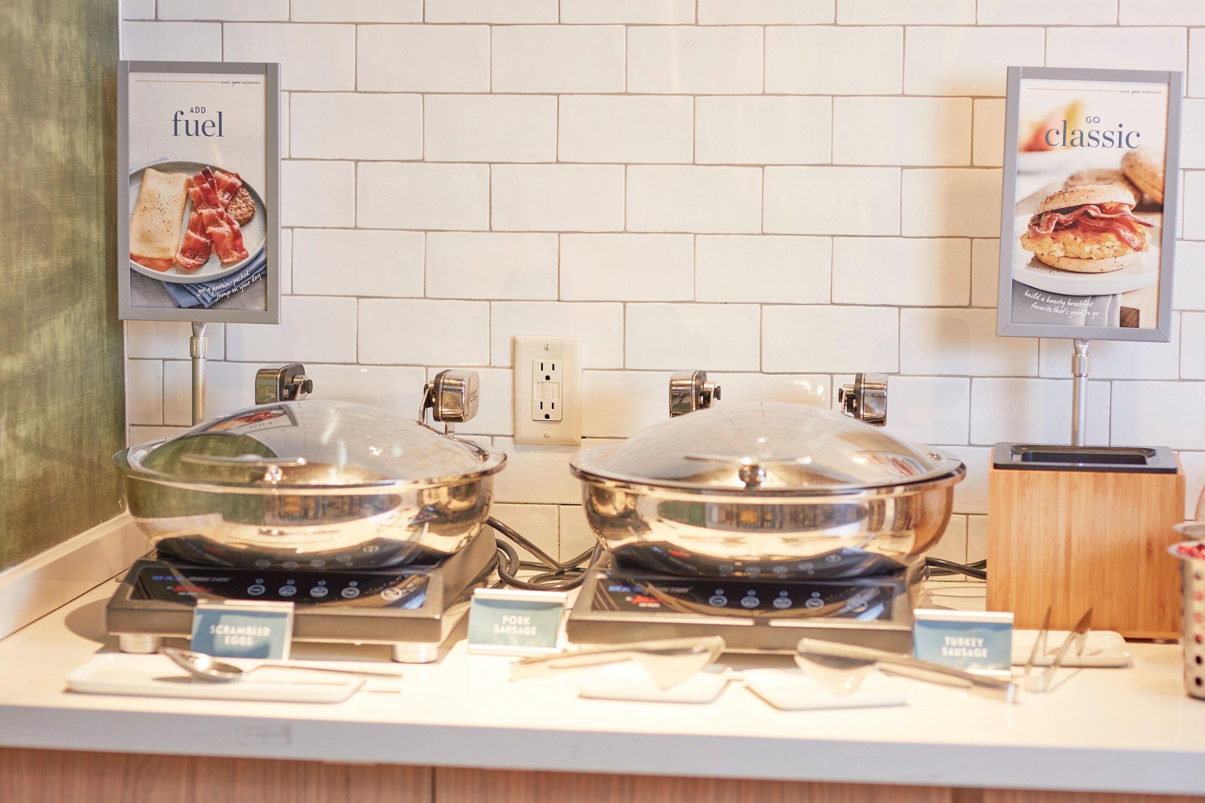 A buffet setup with two large pots of food, a toaster, and a coffee maker.