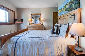 Relax in this serene bedroom with a large bed, nightstand, and mounted TV.