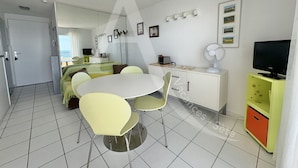 A compact living space with a dining area, kitchenette, and a TV.