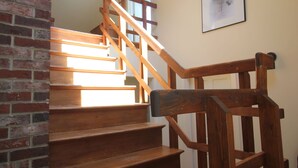 A wooden staircase with a handrail, a chandelier, and a framed picture on the wall.