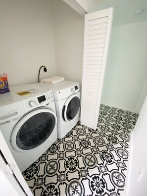 A laundry room with two washing machines, a drying rack, and patterned floor tiles. - Casa Grande - Second Floor (Miami)