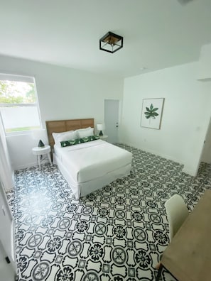 A bedroom with a bed, a bedside table, a chair, a window, and a door. - Casa Grande - Second Floor (Miami)
