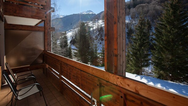 Un balcón de madera con vista a un paisaje montañoso nevado.