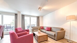 Un salon moderne comprenant un canapé, deux fauteuils, une table basse et un lampadaire.