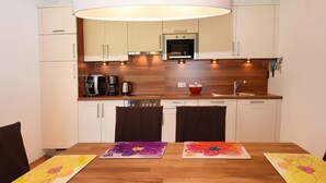 Een moderne keuken met houten kastjes, een inbouwoven en een koffiezetapparaat.