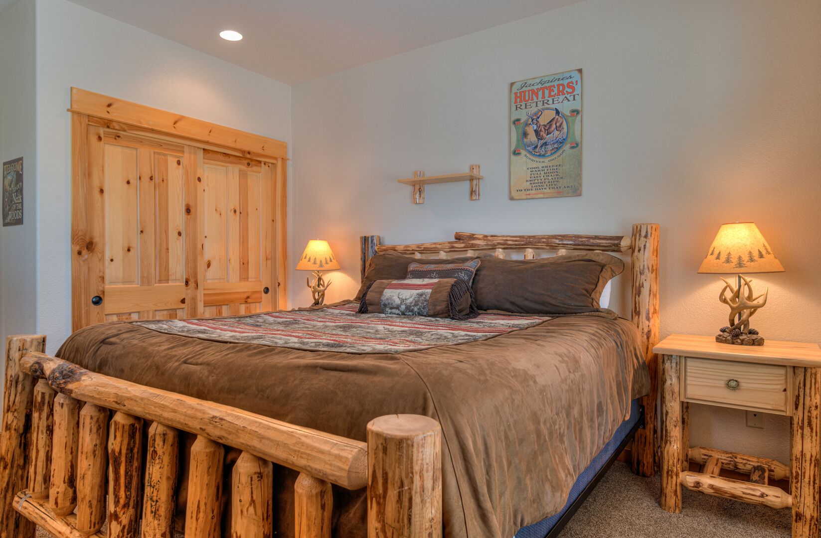 Een kamer in rustieke stijl met een houten bed, twee bedlampen en een poster aan de muur.