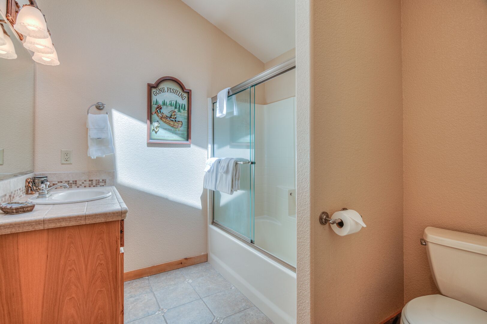 A bathroom with a wooden vanity, a glass shower enclosure, and a toilet.