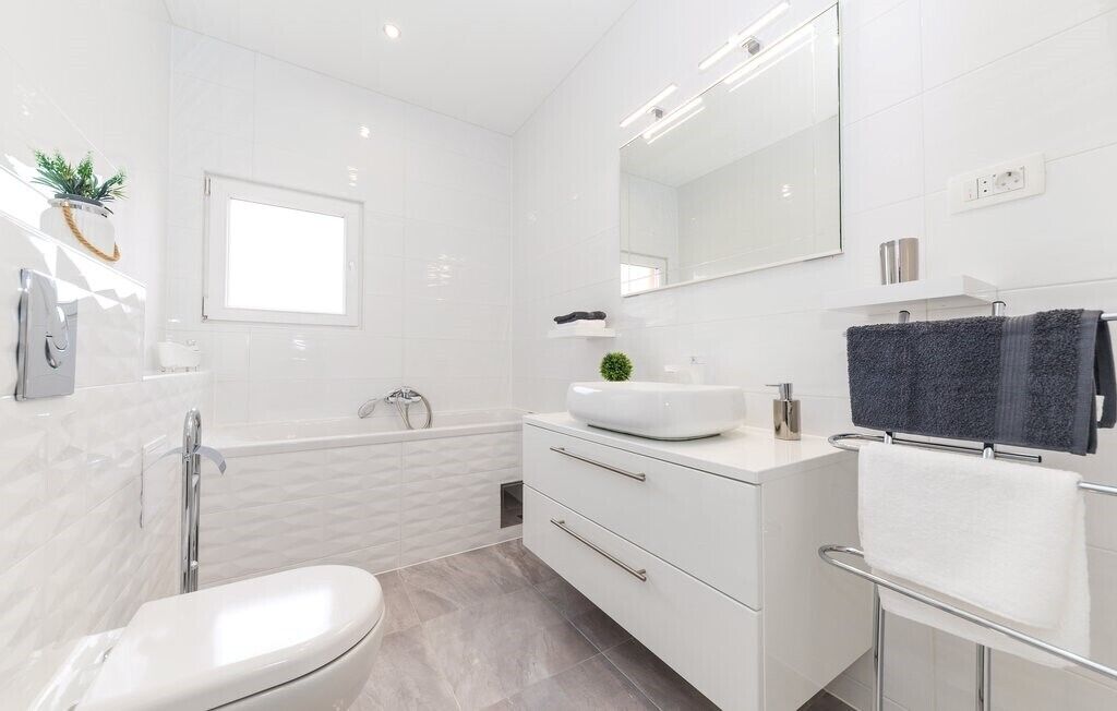 Une salle de bain moderne équipée d’une baignoire, de toilettes, d’un lavabo et d’un meuble-lavabo avec un miroir.