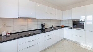 A modern kitchen with white cabinets, a black countertop, and stainless steel appliances. - Villa Lioness in Kastel Luksic, playground & pool (Kastel Luksic)