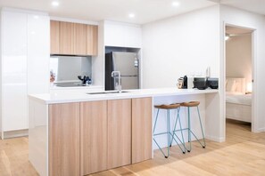 Une cuisine moderne avec un îlot central, des armoires en bois et un tabouret de bar.