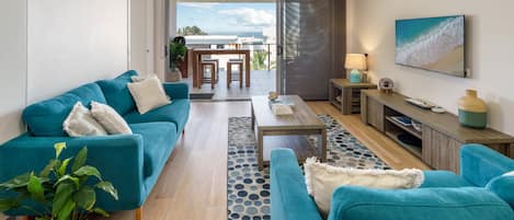 Een moderne woonkamer met turquoise banken, een bijzettafeltje en een tv-meubel.