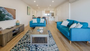 A modern living room with a blue sofa set, a wooden coffee table, and a patterned rug. - Bright Stylish King’s Beach Apartment (Kings Beach)