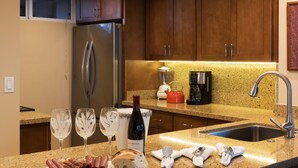A kitchen with granite countertops, stainless steel appliances, and wooden cabinets. - Mahana 604 Oceanfront 1bd/1ba 1 Bedroom Condo by RedAwning (Lahaina)