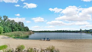 A lakeside beach with lounge chairs and a wooden deck. - Cozy cottage NOW available for short or long term rentals(seasonal) (Michigan City)