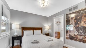 A neatly arranged bedroom with a large bed, bedside tables, and a poster on the wall. - Cozy cottage NOW available for short or long term rentals(seasonal) (Michigan City)
