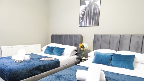 Two twin beds with blue bedding, white pillows, and towels. - Tudors eSuites Three Bedroom House (Coventry)