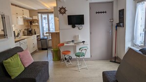 A compact living space with a kitchenette, a dining area, and a television mounted on the wall.