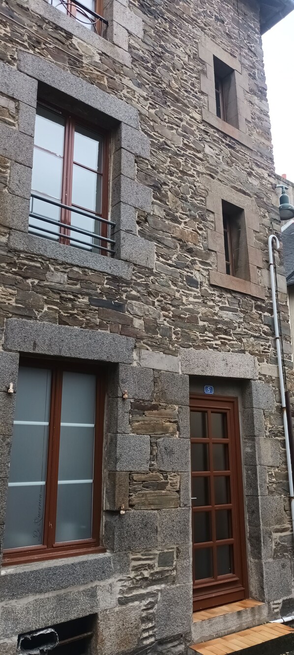 Un edificio de piedra con múltiples ventanas, incluyendo un ventanal grande con marco de madera y una ventana más pequeña con marco de metal.
