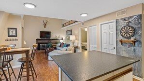 A spacious living room with a fireplace, a dining area with wooden chairs, and a kitchen with a large island.