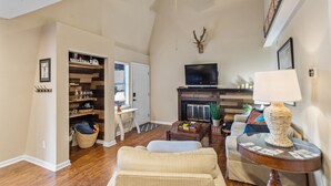 A spacious living room with a fireplace, a television, and a ceiling fan.