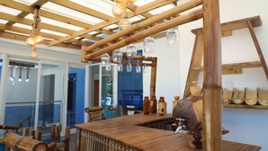 Una zona de bar con barra de madera, luminarias colgantes y una estructura de madera.