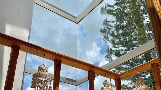 Una habitación con techo de vidrio, vigas de madera y adornos colgantes.