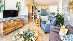 Ein modernes Wohnzimmer mit einem Holzkabinett, einem blauen Sofa, einem Glastisch und einem Fernseher an der Wand.
