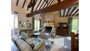 A cozy living room with a fireplace, a sofa, a coffee table, and a television. - Large villa in the heart of the Parc du Perche (Nogent-le-Rotrou)