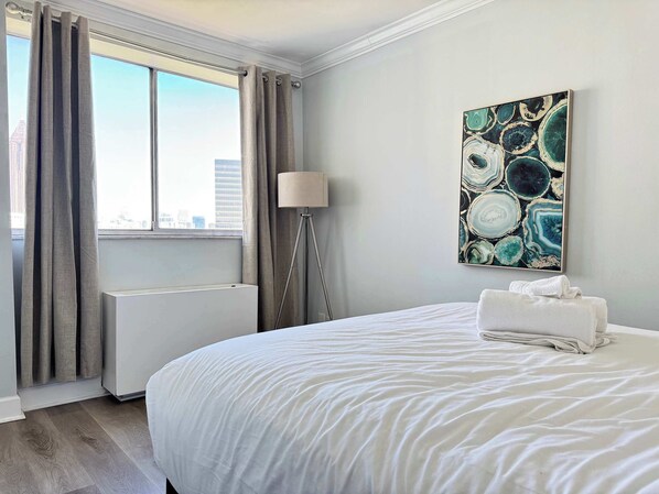 Ein Hotelzimmer mit einem großen Bett, einem Heizkörper, einer Stehlampe und Blick auf die Stadt.