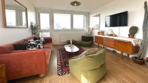 A living room with a sofa, armchair, coffee table, TV, and a wooden cabinet. - Stylish flat near London Bridge with balcony views - Pass the Keys (London)