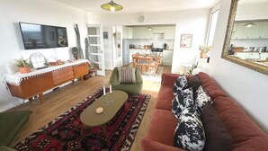 A living room with a sofa, a coffee table, a TV, a dining area, and a kitchen. - Stylish flat near London Bridge with balcony views - Pass the Keys (London)