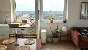 A kitchen with a view, a dining table with placemats, a red sofa, and a potted plant. - Stylish flat near London Bridge with balcony views - Pass the Keys (London)