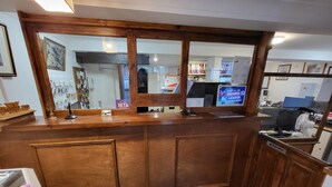 A reception desk with a wooden finish, a glass partition, and a sign indicating tax information. - The Grand Harbour Hotel (Ilfracombe)