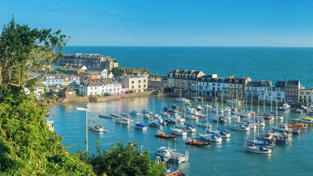 A coastal town with a marina filled with boats, historic buildings, and a clear view of the sea. - The Grand Harbour Hotel (Ilfracombe)