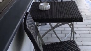 A balcony with a table and chairs, a white vase, and a view of the outdoors. - 1a apartment Sturm (Emmerthal)