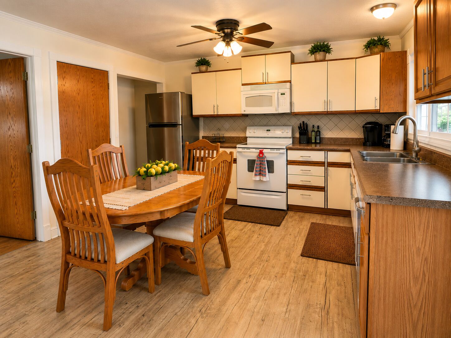 Una cocina con armarios de madera, un refrigerador, un microondas, una estufa y una mesa de comedor con sillas.