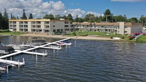 A waterfront hotel with multiple buildings, a dock with boats, and a grassy area with kayaks.