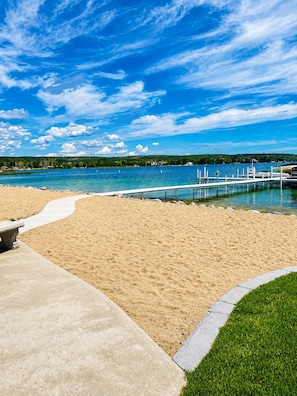 Una spiaggia con una passeggiata in cemento, un molo di legno e un cielo azzurro limpido.