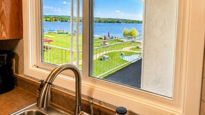 A kitchen with a window overlooking a pool and a lake.