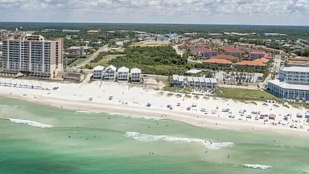 A coastal resort area with beachfront properties, a sandy beach, and a clear view of the ocean.