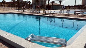 A swimming pool with clear blue water, a lifeguard stand, and lounge chairs around the pool area.