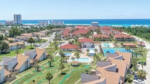 A resort with multiple buildings, a swimming pool, and a view of the ocean.